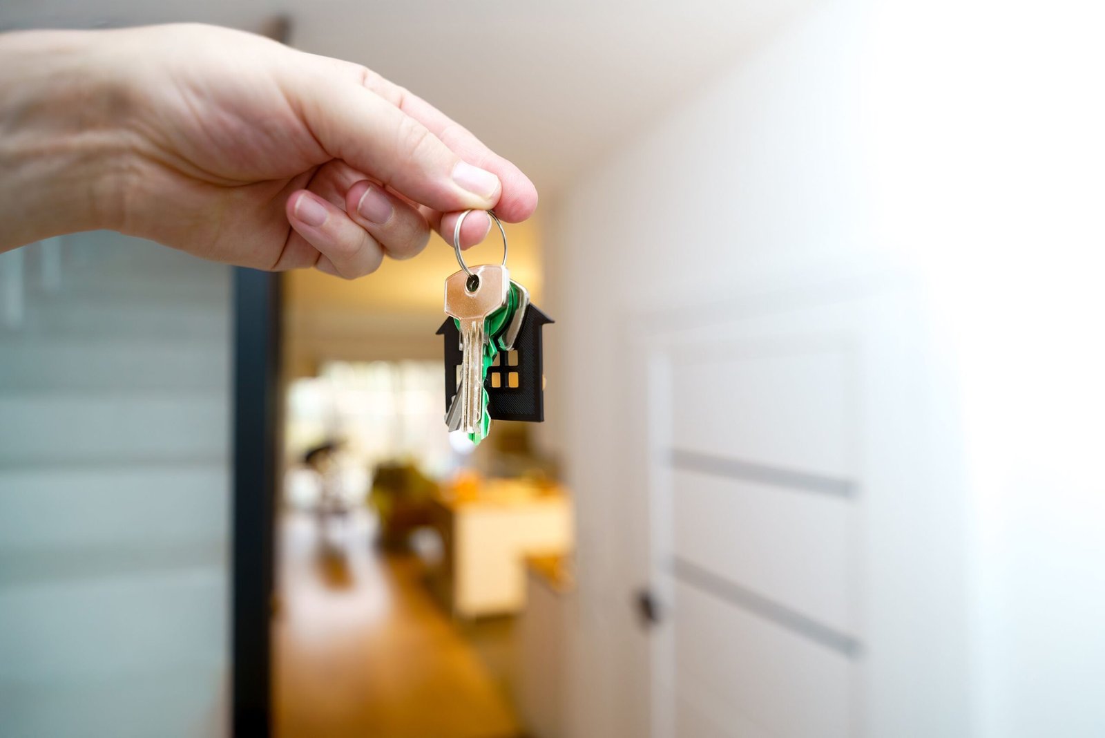 Hand holding house keys inside an apartment