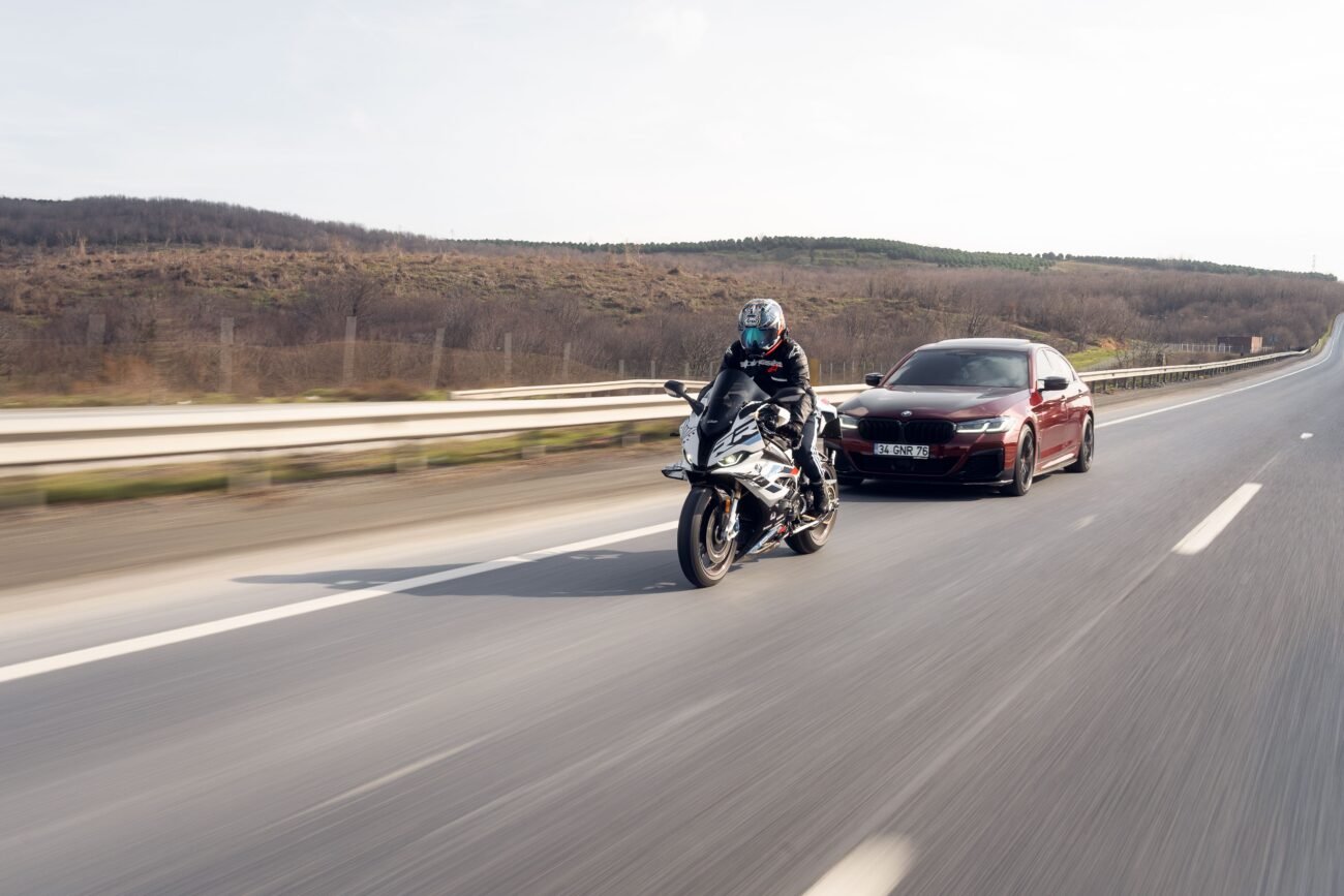 Motorcycle riding alongside a car on a highway, illustrating motorcycle road safety