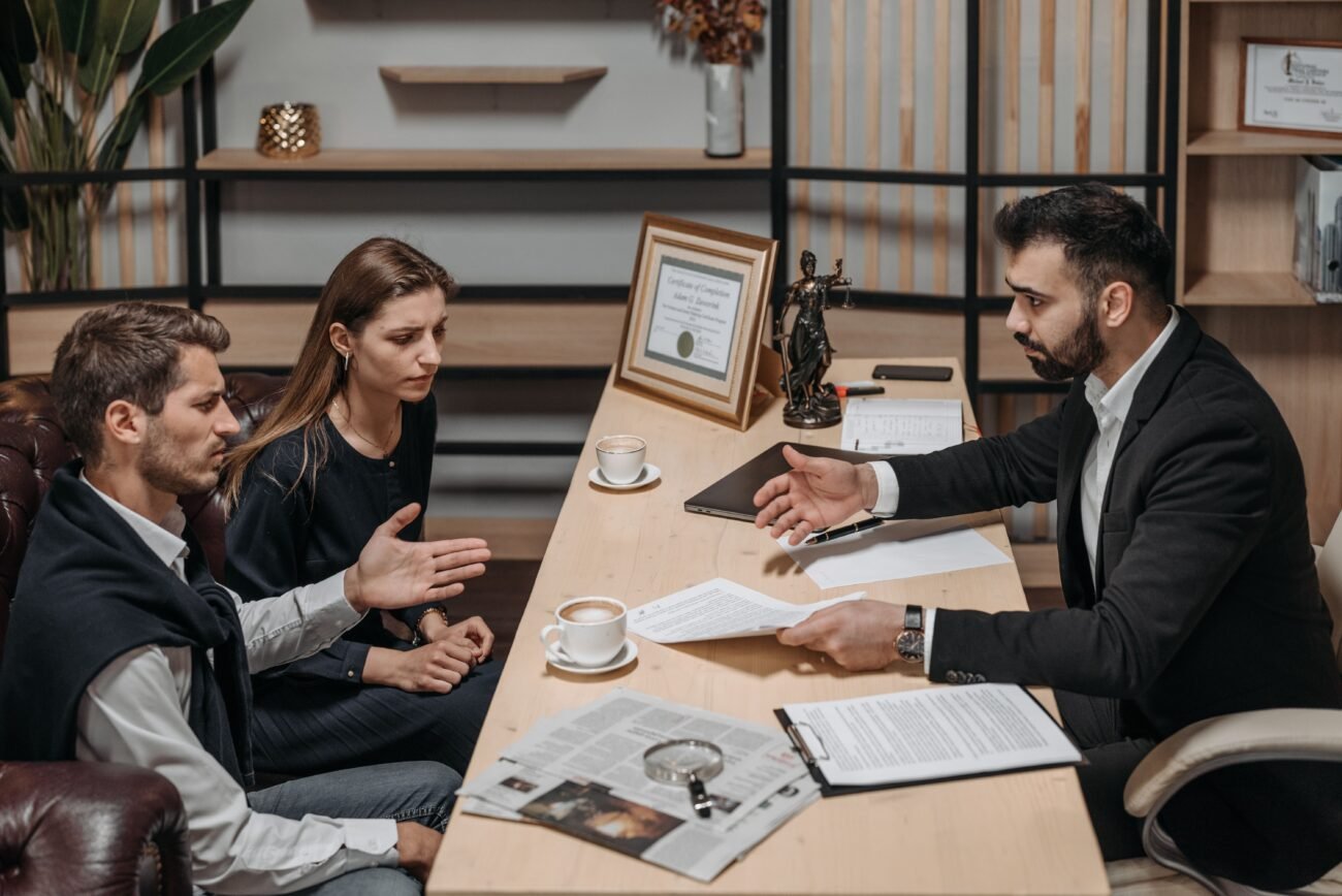 Clients discussing documents with a lawyer, illustrating questions about an auto insurance claim